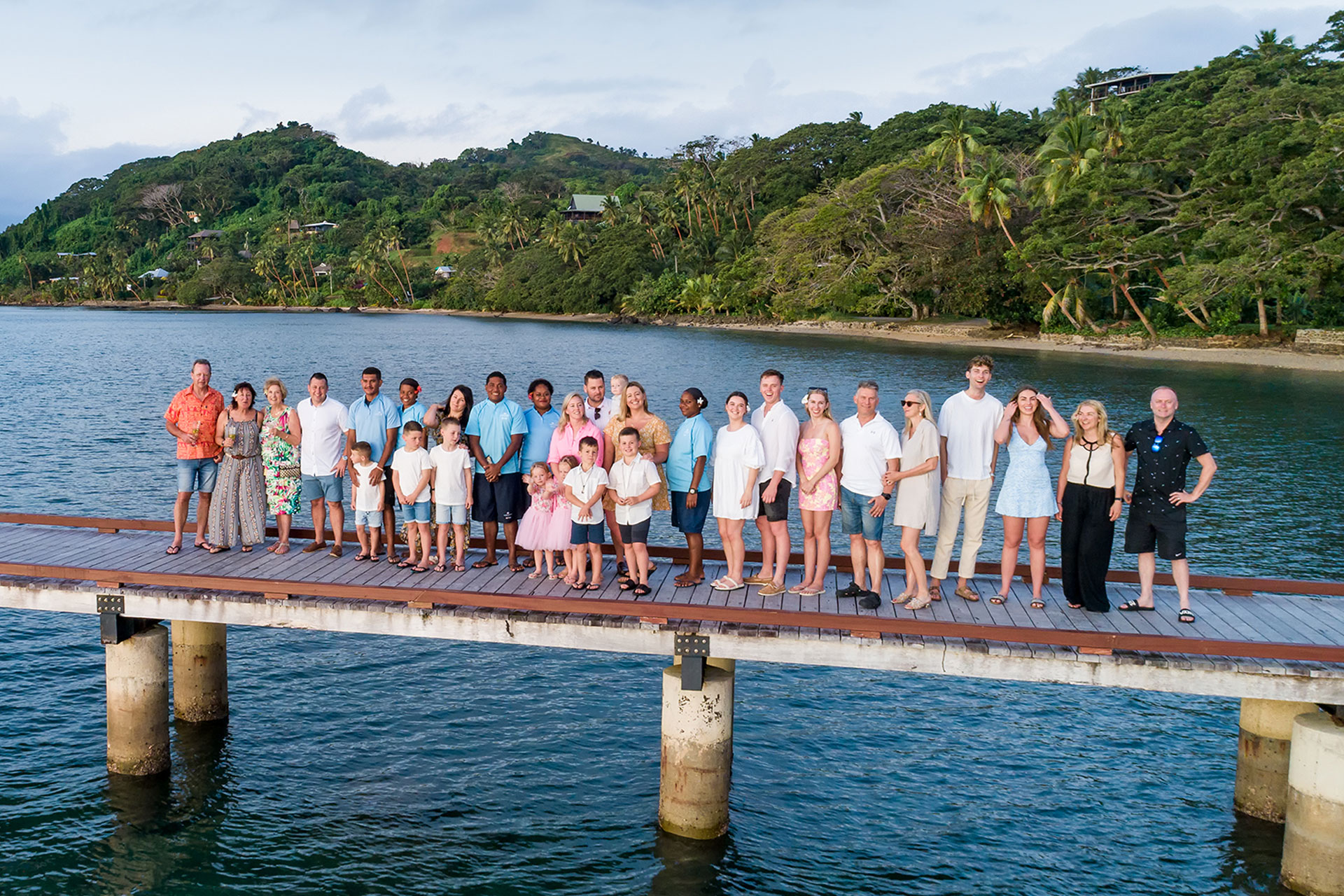 Image shows a multigenerational family alongside resort staff at Jean-Michel Cousteau Resort Fiji, an all-inclusive family resort in Fiji.