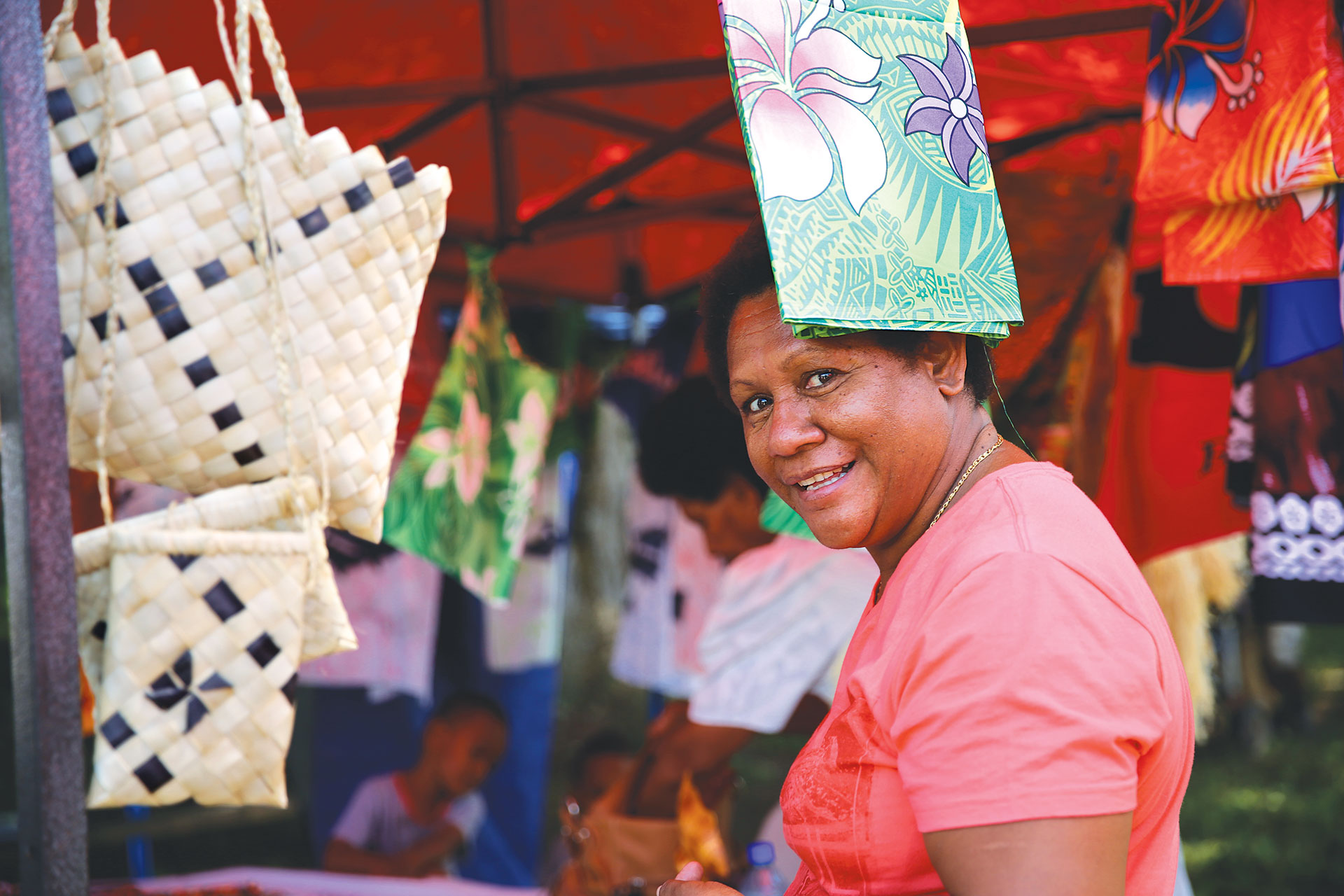 Image of a local women around handcrafted Fijian bags, art and clothing.